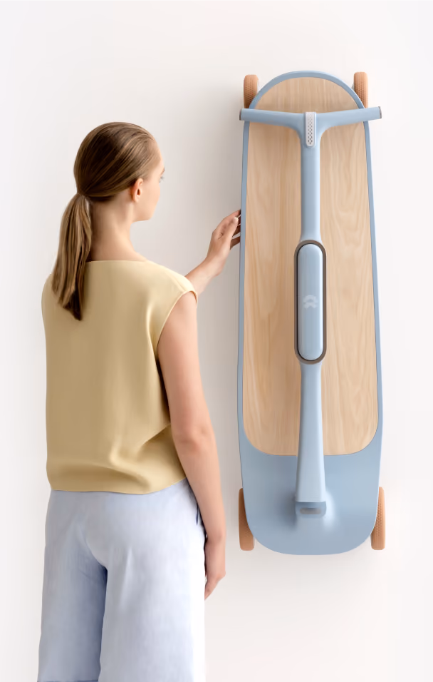 Woman in beige top and light shorts standing next to a modern, blue and wooden electric scooter mounted on wall.