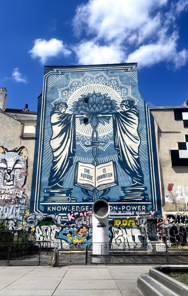 Large mural showing two robed figures holding a flower, with open book saying 'The future is unwritten'.
